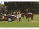 This property offers an equestrian lifestyle, with two women standing next to a horse on a lush, green field next to a luxury car at 12405 Stonelake Ranch Blvd, Thonotosassa, FL 33592