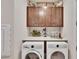Laundry room with upper cabinets, a farmhouse style, and a washer and dryer at 12940 Brookside Moss Dr, Riverview, FL 33579