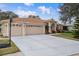 Tan house with three-car garage, basketball hoop, and manicured lawn at 2342 Edelweiss Loop, Trinity, FL 34655