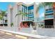 Condo building exterior, featuring a teal and white color scheme, gated entrance, and tropical landscaping at 343 Rex Pl # F, Madeira Beach, FL 33708