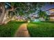 Night view of lush landscaping, a walking path, and building exteriors at 632 Edgewater Dr # 439, Dunedin, FL 34698