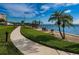Paved walkway winds through a landscaped area with palm trees and benches by the water at 632 Edgewater Dr # 439, Dunedin, FL 34698