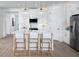 Modern white kitchen with island, stainless steel appliances, and light wood floors at 12269 New Tranquility Path, Venice, FL 34293