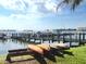 Scenic waterfront view with a wooden dock, moored boats, kayaks, and lush green grass at 130 Banyan Bay Dr, St Petersburg, FL 33705