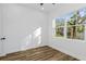 Bright bedroom with wood-look floors and a large window offering a view of the backyard at 1696 Wilmar Ave, Tarpon Springs, FL 34689