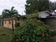 Ranch style home with yellow siding, palm tree and red flowers in front at 1766 Montana Ne Ave, St Petersburg, FL 33703
