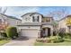 Two-story home with beige exterior, two-car garage, and landscaping at 18811 Deer Tracks Loop, Lutz, FL 33558