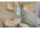 Updated bathroom with marble shower and flooring, white pedestal sink, and window at 2801 Hibiscus W Dr, Belleair Beach, FL 33786