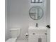 Modern bathroom with white vanity, round mirror, and toilet at 401 Dorchester Pl # 52, Sun City Center, FL 33573