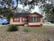 Tan house with red trim, surrounded by trees and landscaping at 819 Twigg St, Brooksville, FL 34601