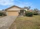 House exterior featuring a tan garage door, stone accents, and landscaping at 14704 Willet Way, Tampa, FL 33625