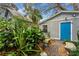Charming side yard with brick path, lush foliage, and blue door at 2886 Bay Shore Dr, Safety Harbor, FL 34695
