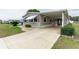 Tan mobile home with carport, landscaping, and paved driveway at 36900 Grace Ave, Zephyrhills, FL 33542