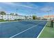 Blue tennis court with net and surrounding fence at 6025 Shore S Blvd # 311, Gulfport, FL 33707
