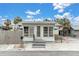 Quaint light green house with a grey roof, small front porch, and fenced yard at 137 91St Ave, Treasure Island, FL 33706