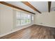 Bright living room featuring wood-look floors, a large window, and decorative wood beam ceiling at 2221 Swedish Dr # 11, Clearwater, FL 33763
