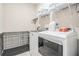 Bright laundry room, washer, dryer, shelving, and dog crate at 34432 Wynthorne Pl, Wesley Chapel, FL 33545