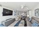 Open concept living room with a large TV, gray sectional, and a view into the kitchen at 7 Elgin Pl # 603, Dunedin, FL 34698