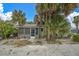 Quaint gray cottage with screened porch nestled amongst palm trees at 130 90Th Ave, Treasure Island, FL 33706