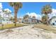 Gray cottage with screened porch, surrounded by palm trees and a sandy yard at 130 90Th Ave, Treasure Island, FL 33706