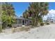 Front view of a charming gray cottage, screened porch, and palm trees at 130 90Th Ave, Treasure Island, FL 33706