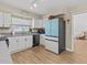 Modern kitchen with white cabinets, light wood floors, and teal refrigerator at 1581 Amberlea S Dr, Dunedin, FL 34698