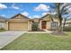 Tan one-story house with attached garage, landscaping, and palm trees at 19820 Morden Blush Dr, Lutz, FL 33558