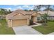 Tan house with a two-car garage and lush landscaping at 19820 Morden Blush Dr, Lutz, FL 33558