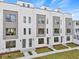 Modern three-story townhouses with gray and white exterior, landscaping, and sidewalks at 2506 W Cleveland St # 18, Tampa, FL 33609