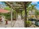 Charming brick pathway under a lush pergola leading to a tranquil pond at 5906 N Kenneth Ave, Tampa, FL 33604