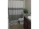 Clean bathroom with a shower/tub combo, gray and white striped shower curtain, and dark wood vanity at 10251 Carloway Hills Dr, Wimauma, FL 33598