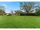 Large grassy front yard with mature trees and neighborhood view at 1383 Glengarry Dr, Palm Harbor, FL 34684