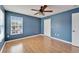 Blue-walled bedroom featuring wood floors and a ceiling fan at 15406 Peach Stone Pl, Ruskin, FL 33573