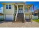 Light green house with double doors, two-car garage, and a stairway leading to the entrance at 1563 Mac Chesney Dr, Tarpon Springs, FL 34689