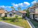 Inviting townhome exterior showcasing a well-maintained lawn, mature landscaping, and a charming walkway to the entrance at 1673 Nash Ct, Dunedin, FL 34698