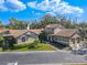 Exterior view featuring a detached garage, well-kept lawn, lush landscaping, and charming architectural details at 1673 Nash Ct, Dunedin, FL 34698