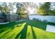 Sunny backyard with artificial turf, wooden fence, and mature trees at 434 29Th N Ave, St Petersburg, FL 33704