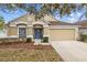 Tan one-story house with blue door, two-car garage, and landscaping at 5310 Algerine Pl, Wesley Chapel, FL 33544