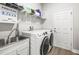 Bright laundry room with stainless steel sink, shelving, and full-size washer and dryer at 10920 Flint Estates Dr, Thonotosassa, FL 33592