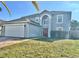 Two-story house with a gray exterior, red door, and a white garage door at 24932 Ravello St, Land O Lakes, FL 34639