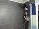 Shower stall with gray tile walls and a three-tiered shower caddy at 6905 Sotra St, Wesley Chapel, FL 33545