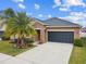 House exterior showcasing a tan facade, dark gray garage door, and stone accents at 11804 Valhalla Woods Dr, Riverview, FL 33579