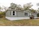 Gray manufactured home with white skirting, wooden steps, and surrounding trees at 12816 Midvale Ave, New Port Richey, FL 34654