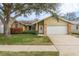 Tan house with brick accents, green lawn, and a white garage door at 3048 Orchard Dr, Palm Harbor, FL 34684