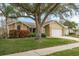 Tan house with a large tree, green lawn, and white garage door at 3048 Orchard Dr, Palm Harbor, FL 34684