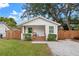 Charming white bungalow with a brown porch, wood fence, and a gravel driveway at 6297 29Th N St, St Petersburg, FL 33702
