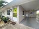 Front view of a house with a lime green door, landscaping, and carport at 883 Sky Loch S Dr, Dunedin, FL 34698