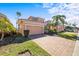 Two-story house with a beige exterior, a two-car garage, and a brick driveway at 1613 Sand Key Estates Ct, Clearwater, FL 33767
