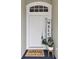 White front door with welcome mat and plant at 25406 Lexington Oaks Blvd, Wesley Chapel, FL 33544