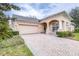 Brick driveway leading to a tan house with garage at 27325 Mistflower Dr, Wesley Chapel, FL 33544